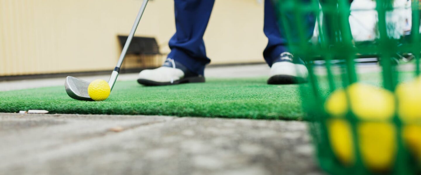 golfer standing on driving range matted station